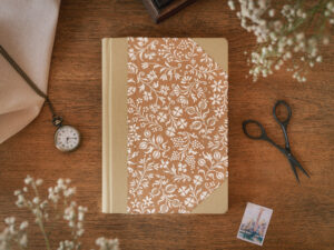 Mały notes w stylu vintage z okładką w kwiaty leży na stole.